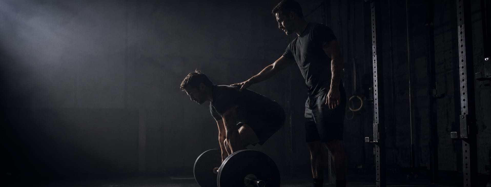 A coach correcting a lifter's set-up position during a session.